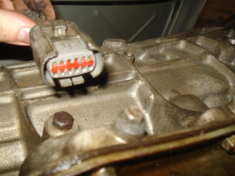 1991 Ford Bronco - Close-up of an electrical connector being attached to a vehicle's engine block, likely during a repair or maintenance procedure.