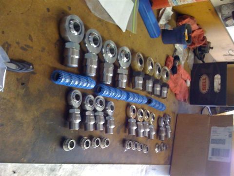 2009 Suzuki Samurai - Various rod ends and hardware are organized on a wooden surface.