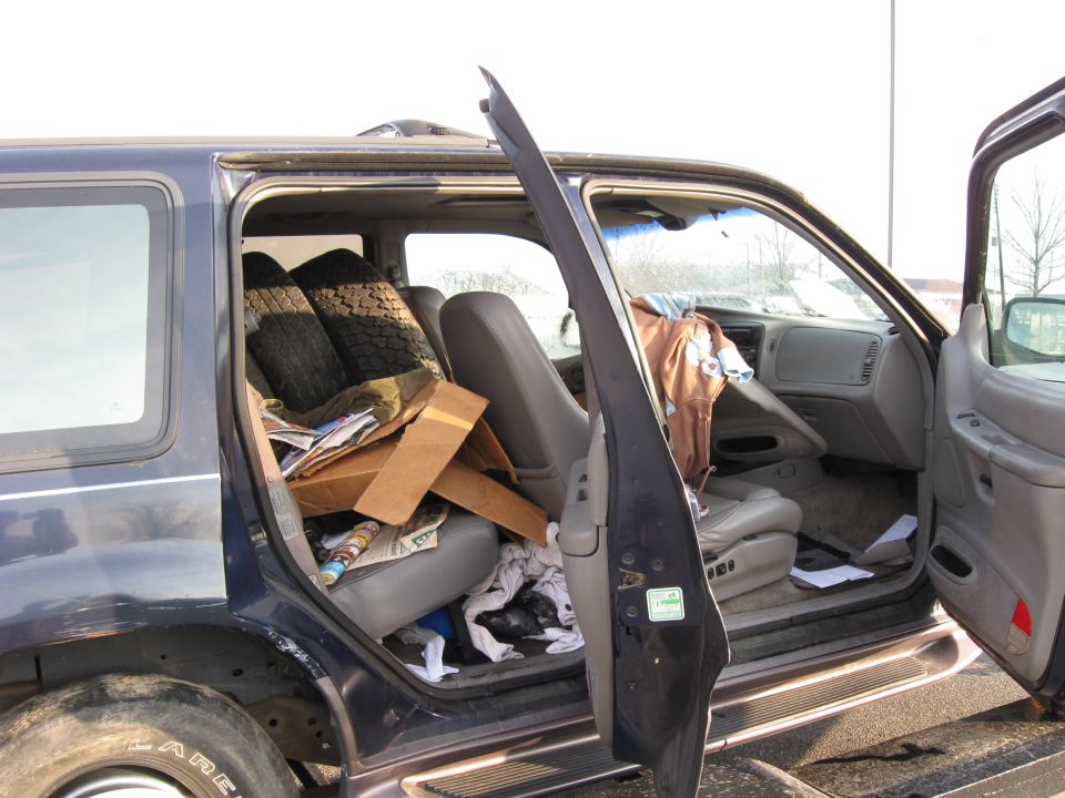 Open passenger side of a dark blue SUV filled with boxes and clutter