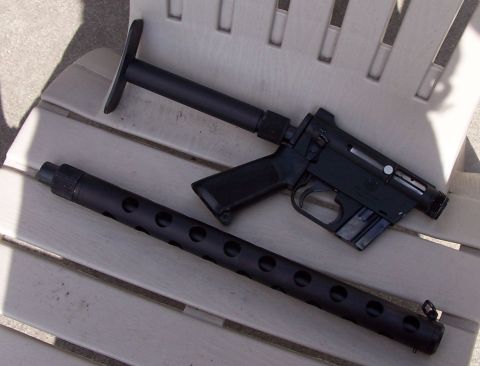 1990 Ford Bronco - Two firearm components, a receiver and a perforated barrel shroud, rest on a slatted surface.