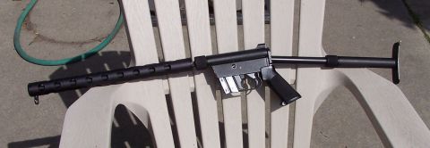 1990 Ford Bronco - A black submachine gun is placed on a white plastic chair outdoors, with a green hose visible to the side.