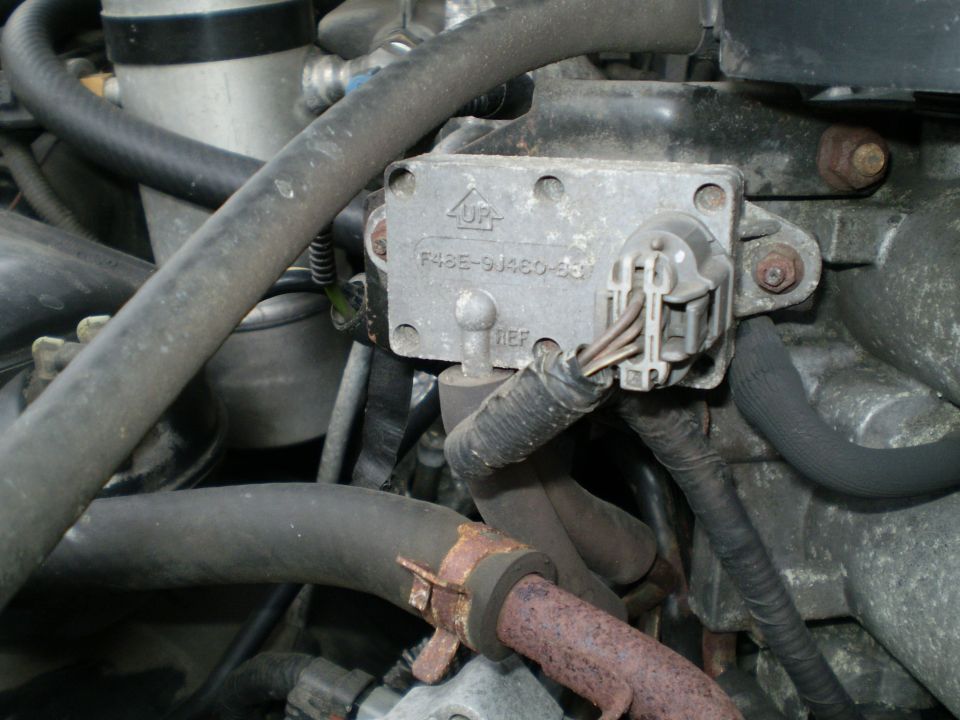 Engine part stamped F48E-9J460-BB with electrical connector and vacuum hoses