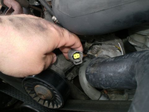 1996 Ford Bronco - Close-up view of a hand disconnecting an electrical connector within the engine bay.