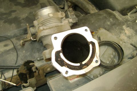 1992 Ford Crown Victoria - Close-up of a dirty throttle body and intake manifold, likely during EGR channel cleaning.