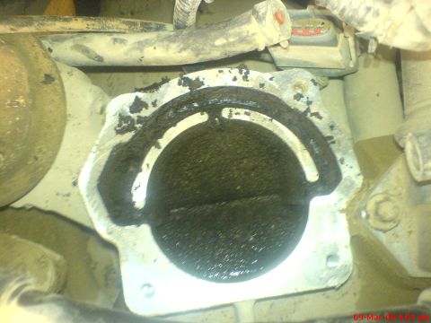 1992 Ford Crown Victoria - Top-down view into a throttle body still bolted to the intake, its bore and closed throttle plate caked with thick black carbon and the hor…