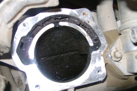 1992 Ford Crown Victoria - Flash-lit close-up straight into an aluminum throttle body bore on the engine, with the closed throttle plate and bore walls completely bla…