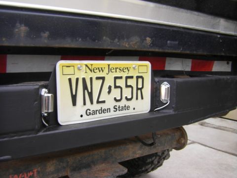 1989 Ford Bronco - Close-up of a black rear bumper a New Jersey license plate and two small lights.
