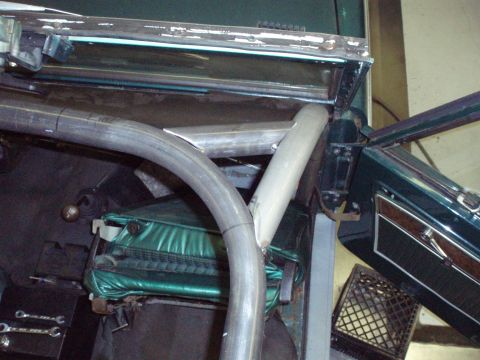 1977 Ford Bronco - Roll cage tubing is being installed inside the green interior of a 1977 Ford Bronco, visible around the manual transmission shifter.
