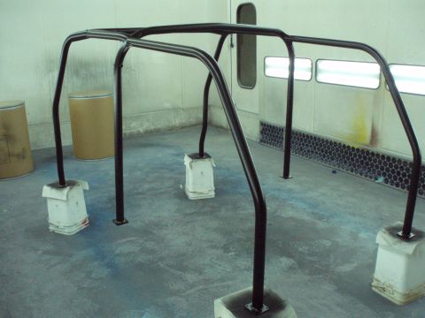1977 Ford Bronco - Roll cage assembly being prepped or painted inside a spray booth.