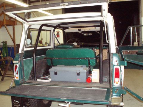 1977 Ford Bronco - The open tailgate reveals the interior of a 1977 Ford Bronco, green upholstery and a toolbox.