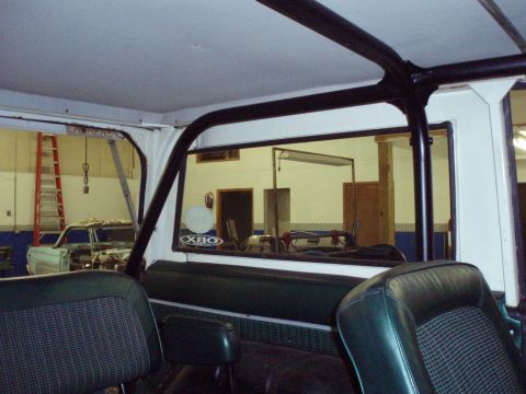 1977 Ford Bronco - Interior of a 1977 Ford Bronco, showing the roll cage and seats. A second vehicle is visible in the background.