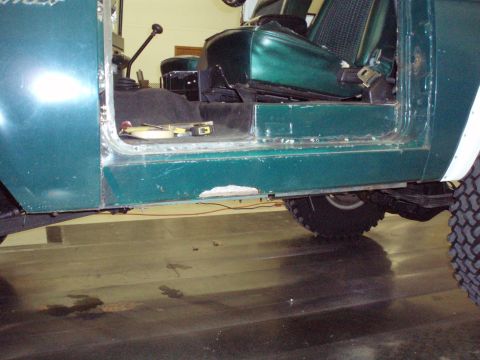 1977 Ford Bronco - Close-up view of the interior and rocker panel of a green Ford Bronco, showing some wear and tear.