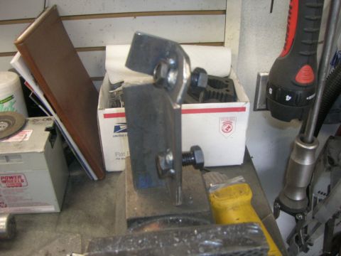 1996 Ford Bronco - A rough-cut steel bracket or mount clamped upright in a bench vise, with a large bolt and nut through a slotted end. A USPS flat-rate box,…