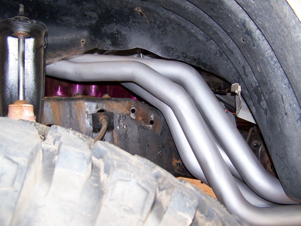 Exhaust headers and suspension components visible near a large tire