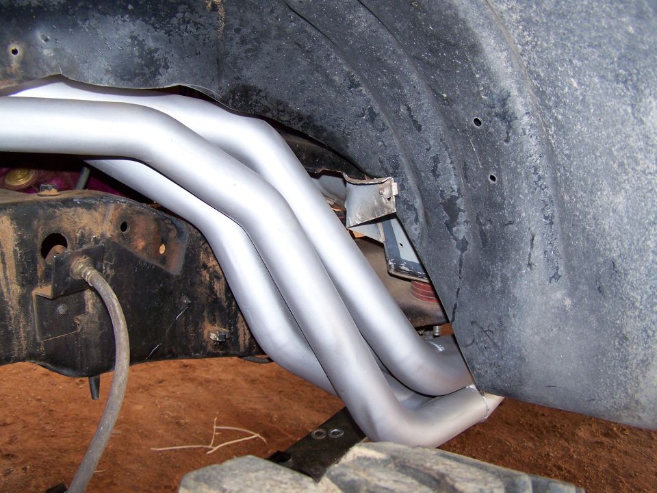 exhaust headers installed on a vehicle frame, close up view