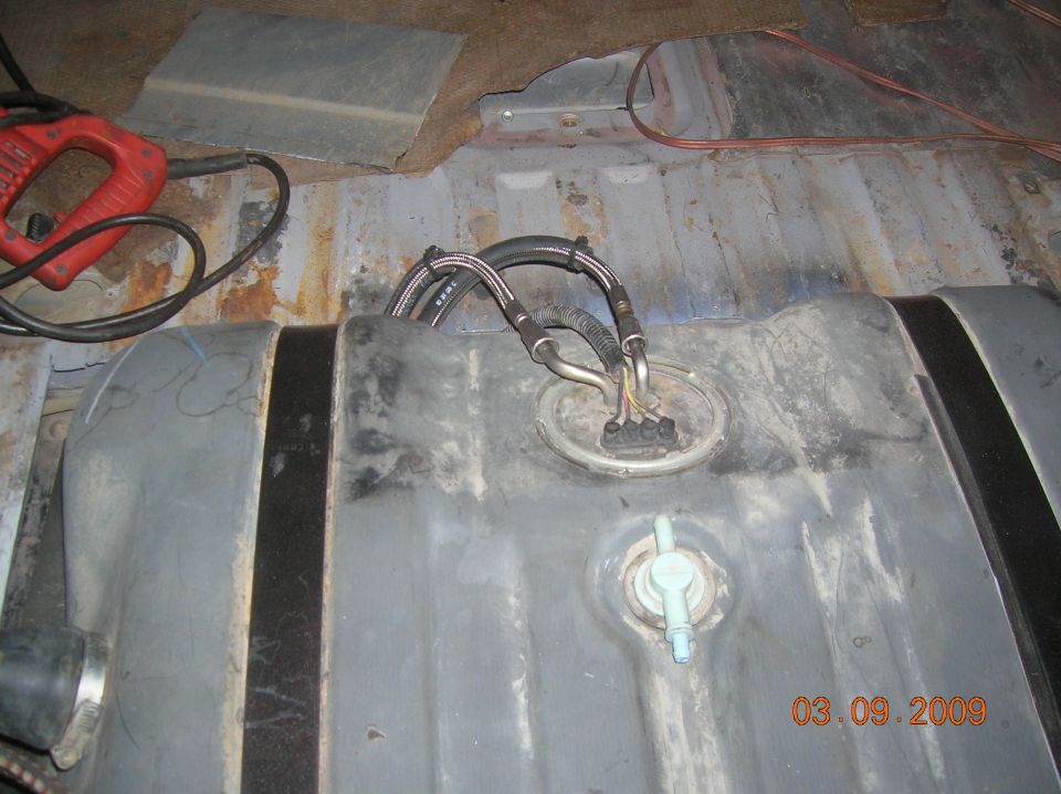 Metal fuel tank with sending unit and hoses removed in workshop