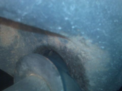 1995 Ford Bronco - A close-up view of a vehicle's undercarriage reveals a dark, textured component with a visible hole.