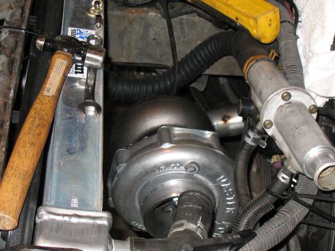 2001 Pontiac Trans Am - A turbocharger is being installed next to the radiator, with tools present in the engine compartment.