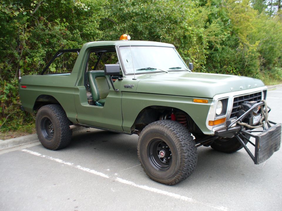 Green 1978 Ford Bronco with aftermarket bumper and roll cage