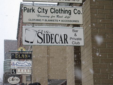 1992 Ford Bronco - Signs for Park City Clothing Co. and The Sidecar Bar & Private Club are visible in a snowy environment.