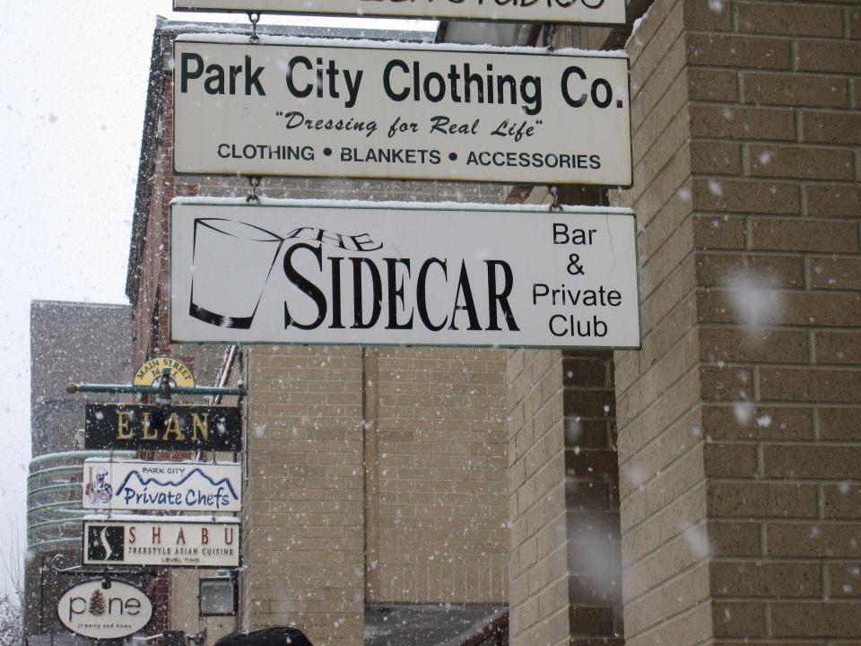 Multiple signs for businesses hang on a brick building in the snow