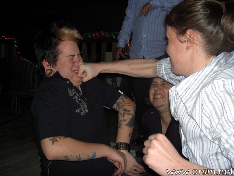 Person punching another person in the face, with a third person watching