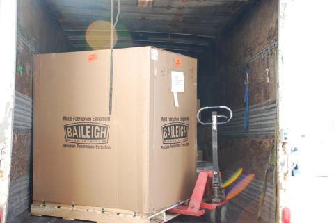 1996 Ford Bronco - A large box containing metal fabrication equipment is being loaded into a truck trailer.