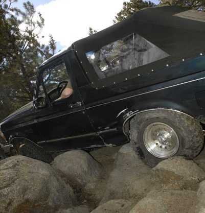 1995 Ford Bronco - This Ford Bronco is navigating a rocky trail, with its tires gripping the uneven terrain.