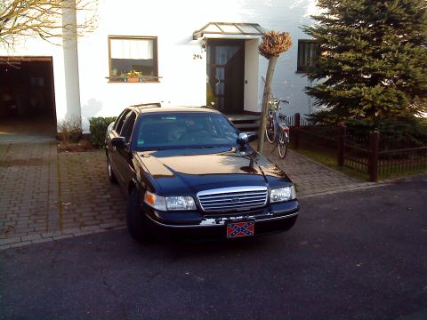 1998 Ford Crown Victoria - A black 1998 Ford Crown Victoria is parked in a driveway in front of a house.
