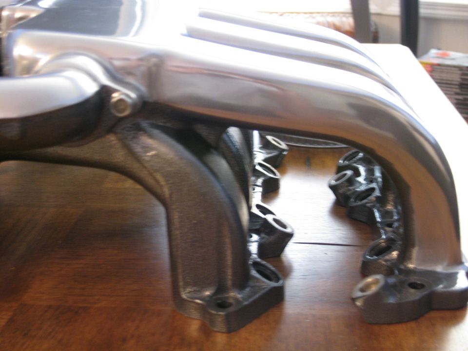 Intake manifold with polished runners and cast iron base on a wooden surface