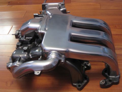 1994 Ford Probe - Polished intake manifold shown from the side on a wooden floor.