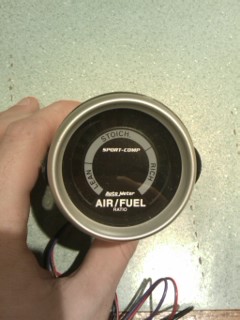 1987 Mazda RX-7 - Close-up of an air/fuel ratio gauge, held in a hand.