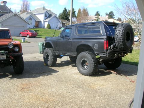 1996 Ford Bronco - A lifted black Ford Bronco is parked in a driveway next to another off-road vehicle.