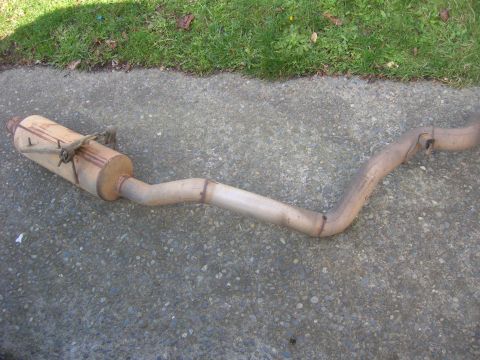 1996 Ford Bronco - This is a used exhaust system part, likely a muffler and pipe assembly, resting on a concrete surface.