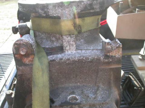 1990 Ford Bronco - Close-up of a weathered engine block secured with a yellow strap, showing signs of rust and wear.