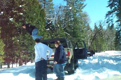 1989 Ford Bronco - A group of people are gathered around a tan 1989 Ford Bronco parked in a snowy area with trees.