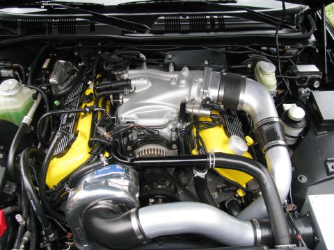 2003 Mercury Marauder - Close-up of a modified V8 engine a prominent supercharger and bright yellow valve covers.