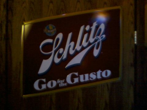 1985 Ford LTD Crown Victoria - A Schlitz beer sign with the slogan 'Go for the Gusto' is mounted on a wooden wall.