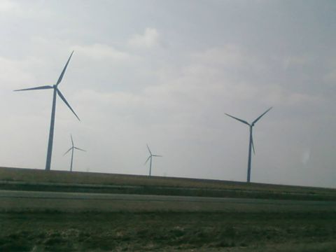 1985 Ford LTD Crown Victoria - Wind turbines are visible on a hill, with a road in the foreground.