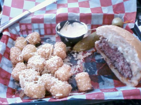 1985 Ford LTD Crown Victoria - A burger and tater tots are served in a checkered basket with a side of dipping sauce.