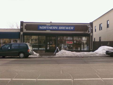 1985 Ford LTD Crown Victoria - A dark green minivan is parked on the street in front of the Northern Brewer store, with snow visible on the ground.