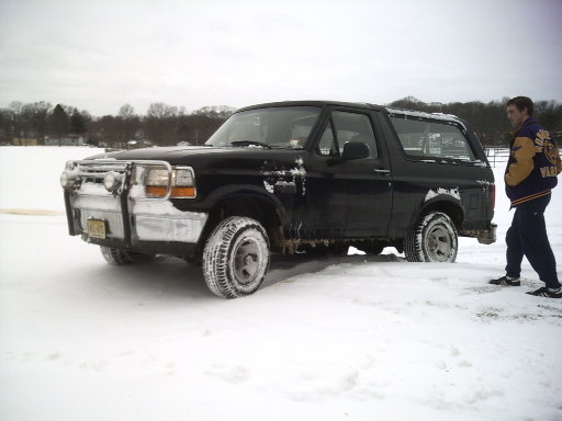Black 1996 Ford Bronco in snow with a person standing next to it