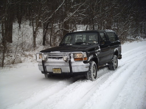 Black 1996 Ford Bronco driving on a snowy road