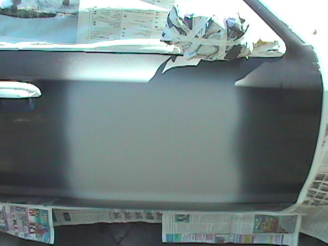 Car door masked with newspaper, freshly sprayed with gray primer during paint prep