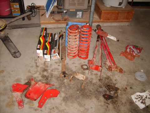 1989 Ford Bronco - Various vehicle parts, including springs and shocks, are laid out on a garage floor.
