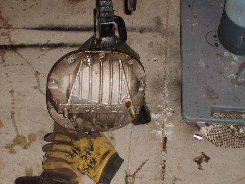 1989 Ford Bronco - A differential cover, likely from a Ford vehicle, is shown hanging from a hoist with work gloves nearby.
