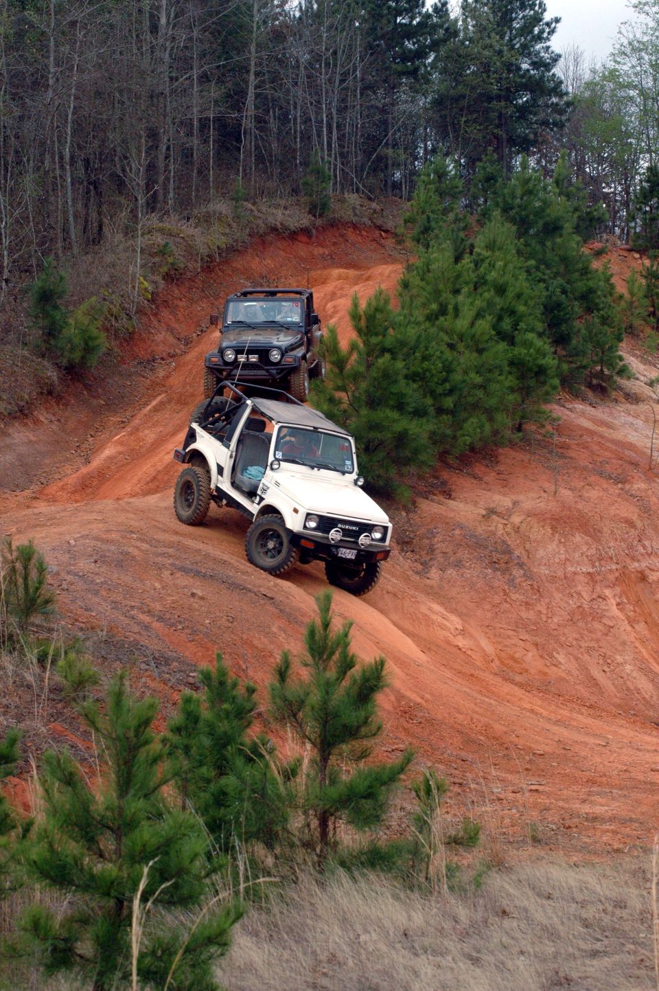 White Suzuki Samurai descending a red-clay off-road trail with a Jeep behind