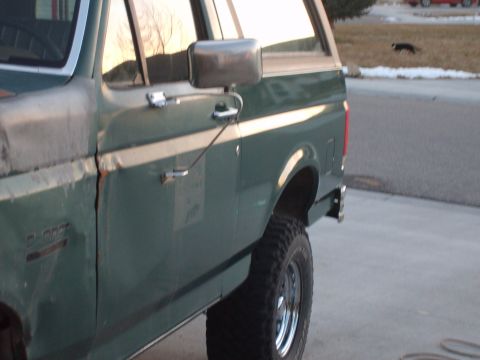 1989 Ford Bronco - Side profile of a green 1989 Ford Bronco, chrome trim and off-road tires.