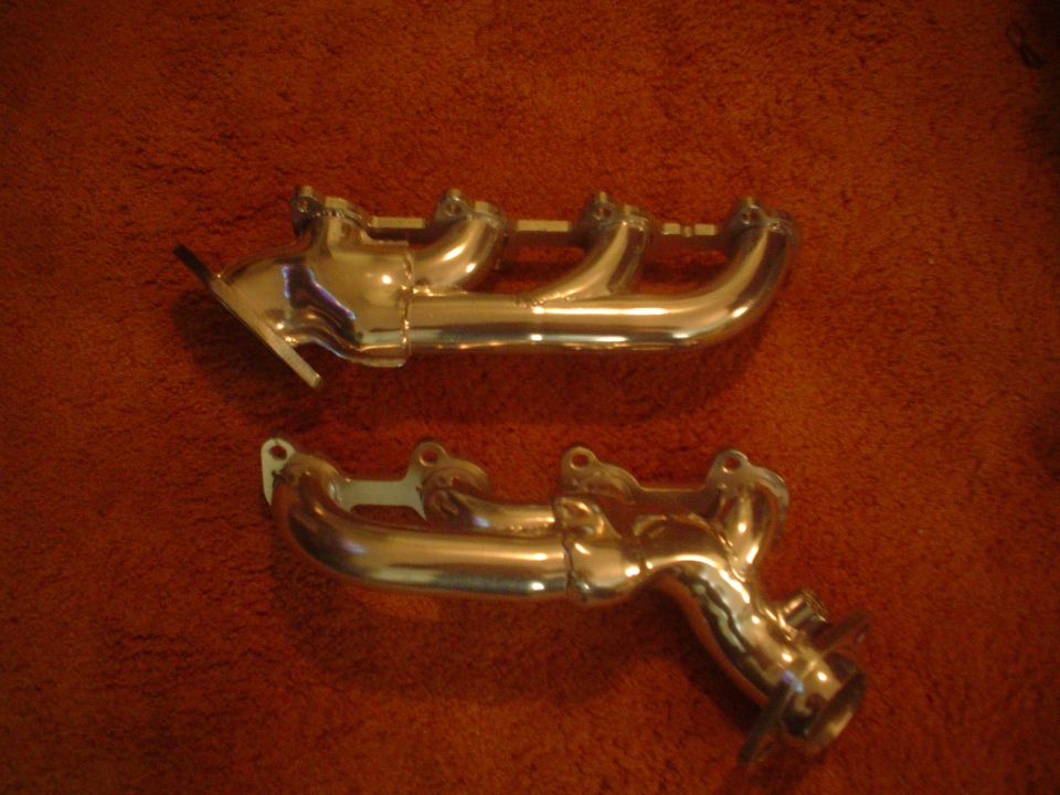 two chrome exhaust manifolds on a brown surface