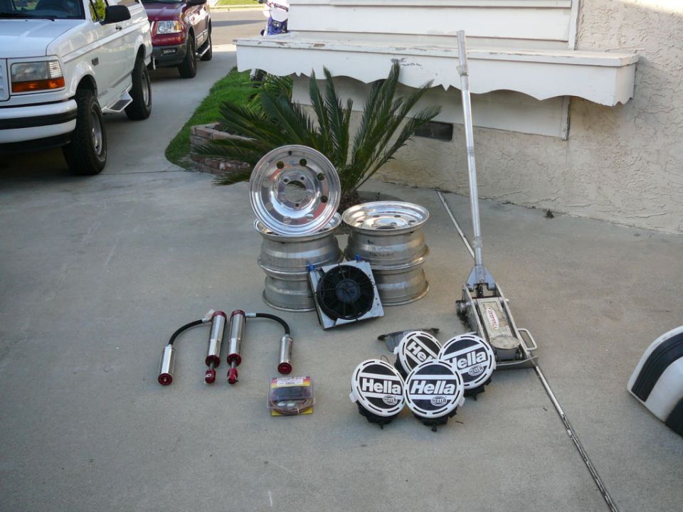 White 1988 Ford Bronco and red pickup truck with parts on driveway